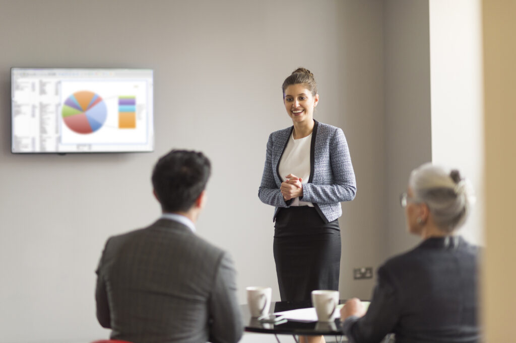 A young professional delivering a business presentation in front of her clients.